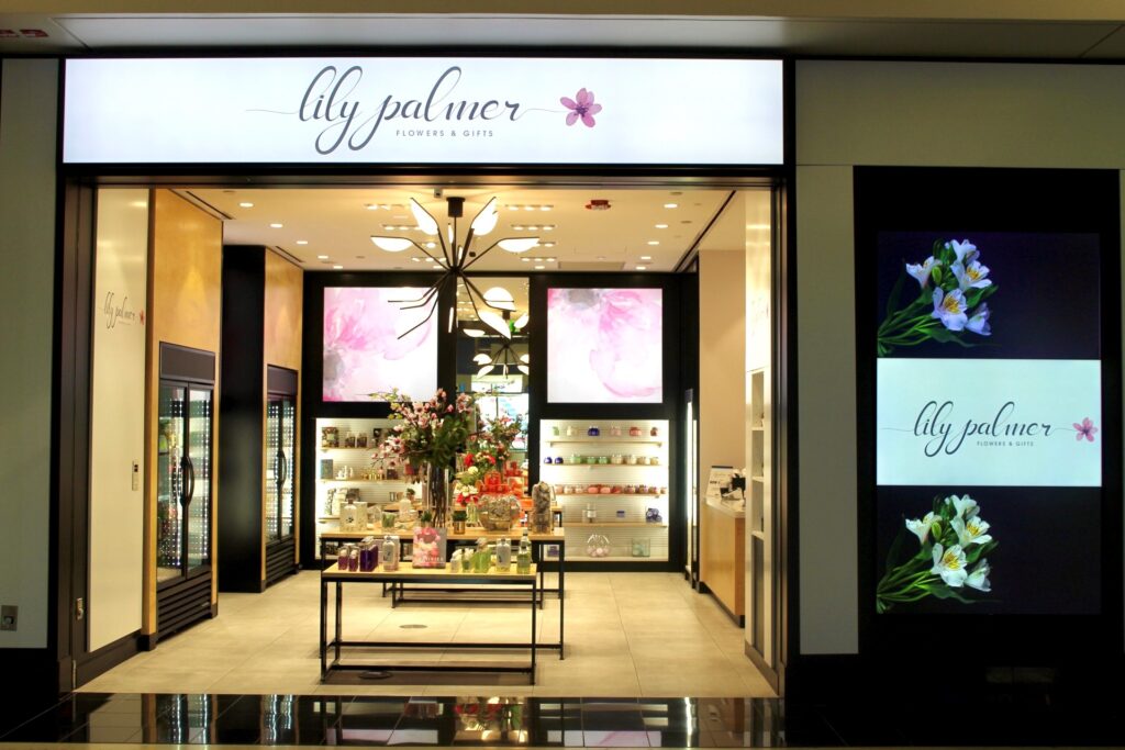 Lily Palmer flower shop entrance with floral displays and digital signage.