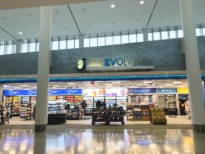 Evolve store at airport with shelves of snacks and beverages.