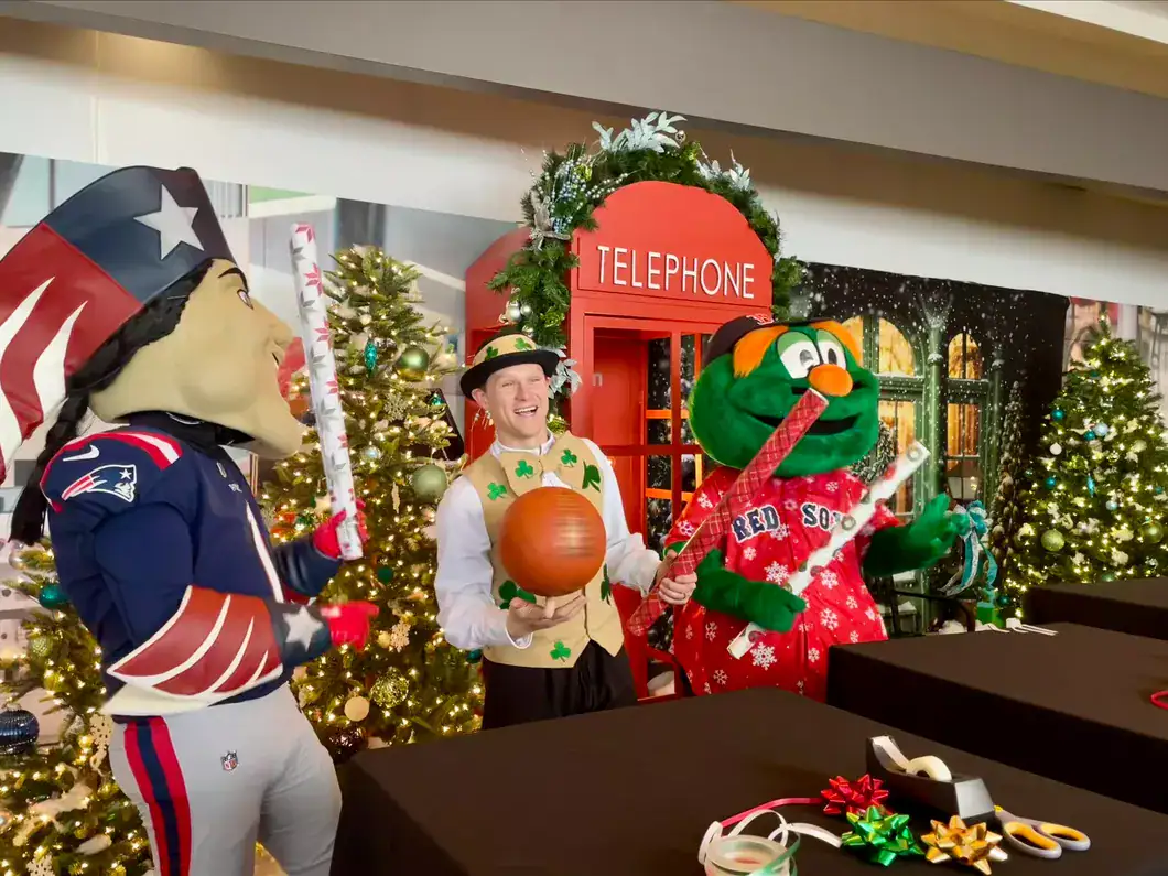 Festive holiday scene with mascot characters, a person holding a pumpkin, and Christmas decorations.