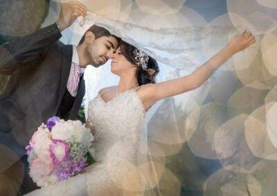 A bride and groom kissing in front of a bokeh background.