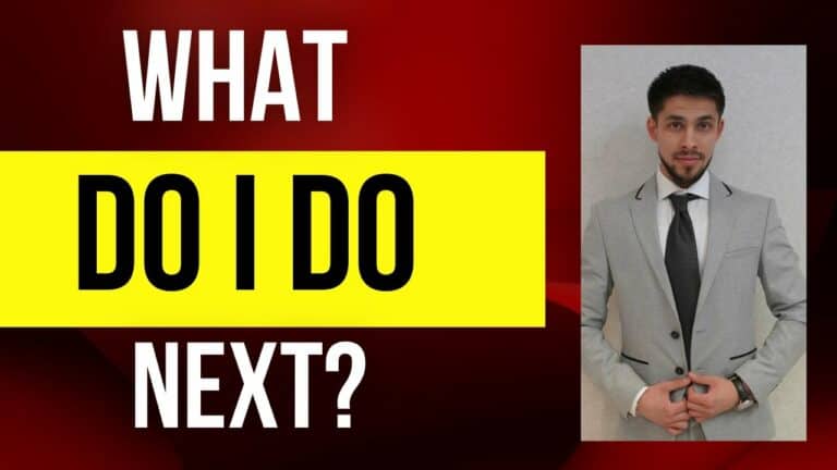 Business professional in a gray suit with a black tie posing confidently.