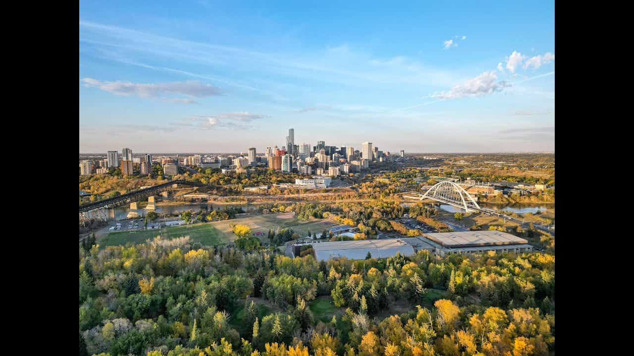 Vibrant aerial view of downtown Edmonton with lush green parks and clear blue skies.