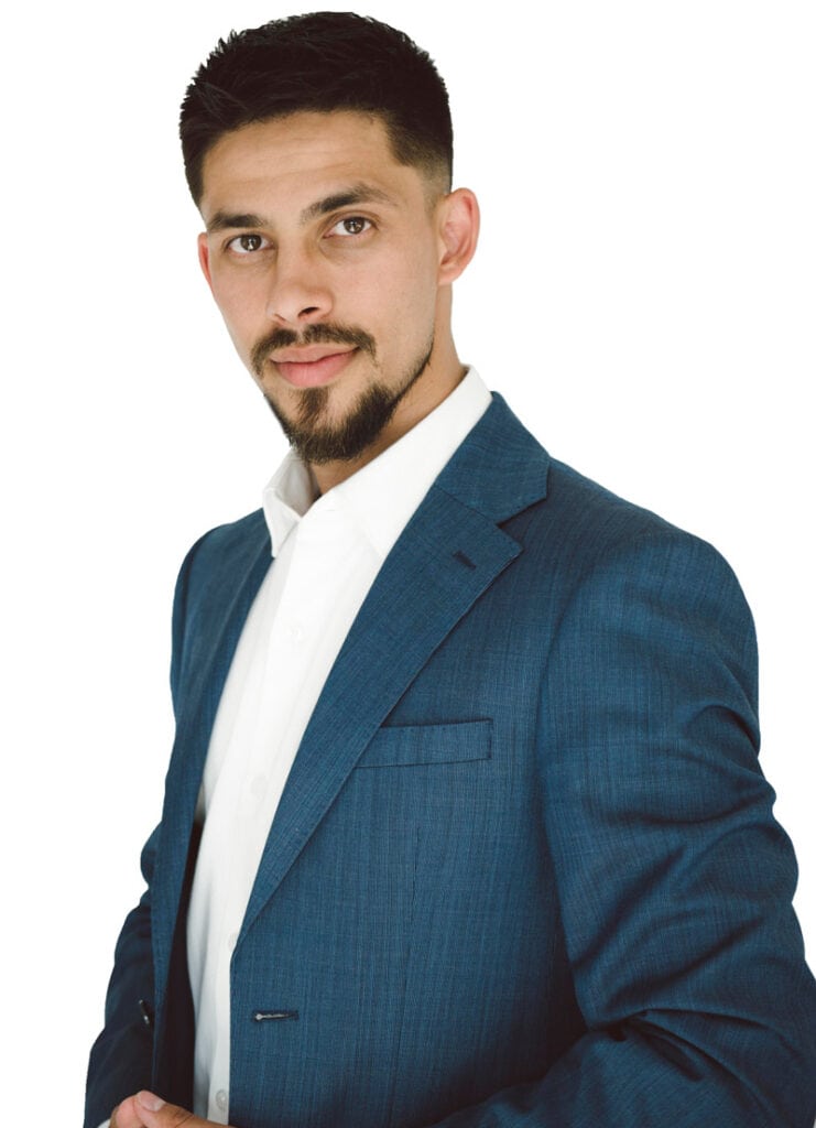 Male professional in formal business attire, wearing a blue suit with a white shirt, looking confidently at the camera, isolated on a white background.