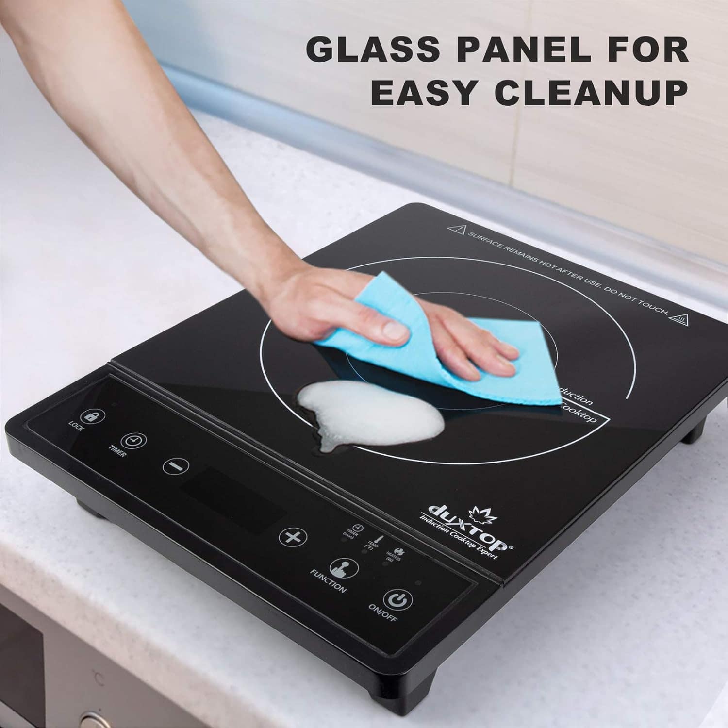 Cleansing a glass electric cooktop with a blue microfiber cloth showcasing easy cleanup and maintenance for safe kitchen appliances