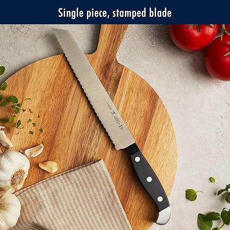 Sharp kitchen knife with a serrated edge on a wooden cutting board surrounded by fresh tomatoes garlic and herbs for meal prep and healthy cooking