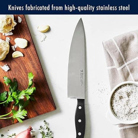 Sharp stainless steel kitchen knife on white countertop with herbs and garlic emphasizing high quality cooking tools from Meals in Motion