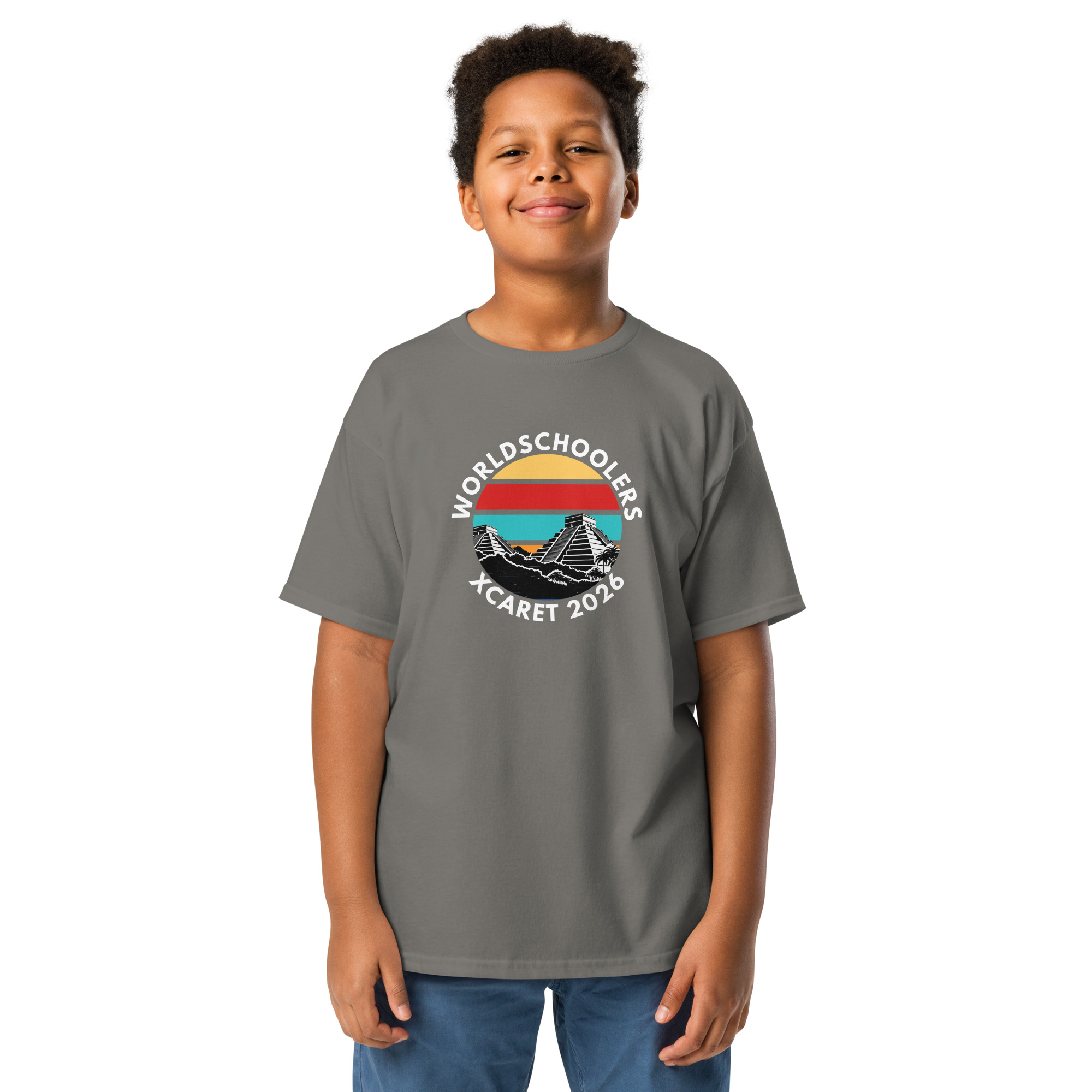 Young boy wearing a gray Xcaret 2026 youth classic T-shirt with a graphic design, standing confidently against a plain white background.