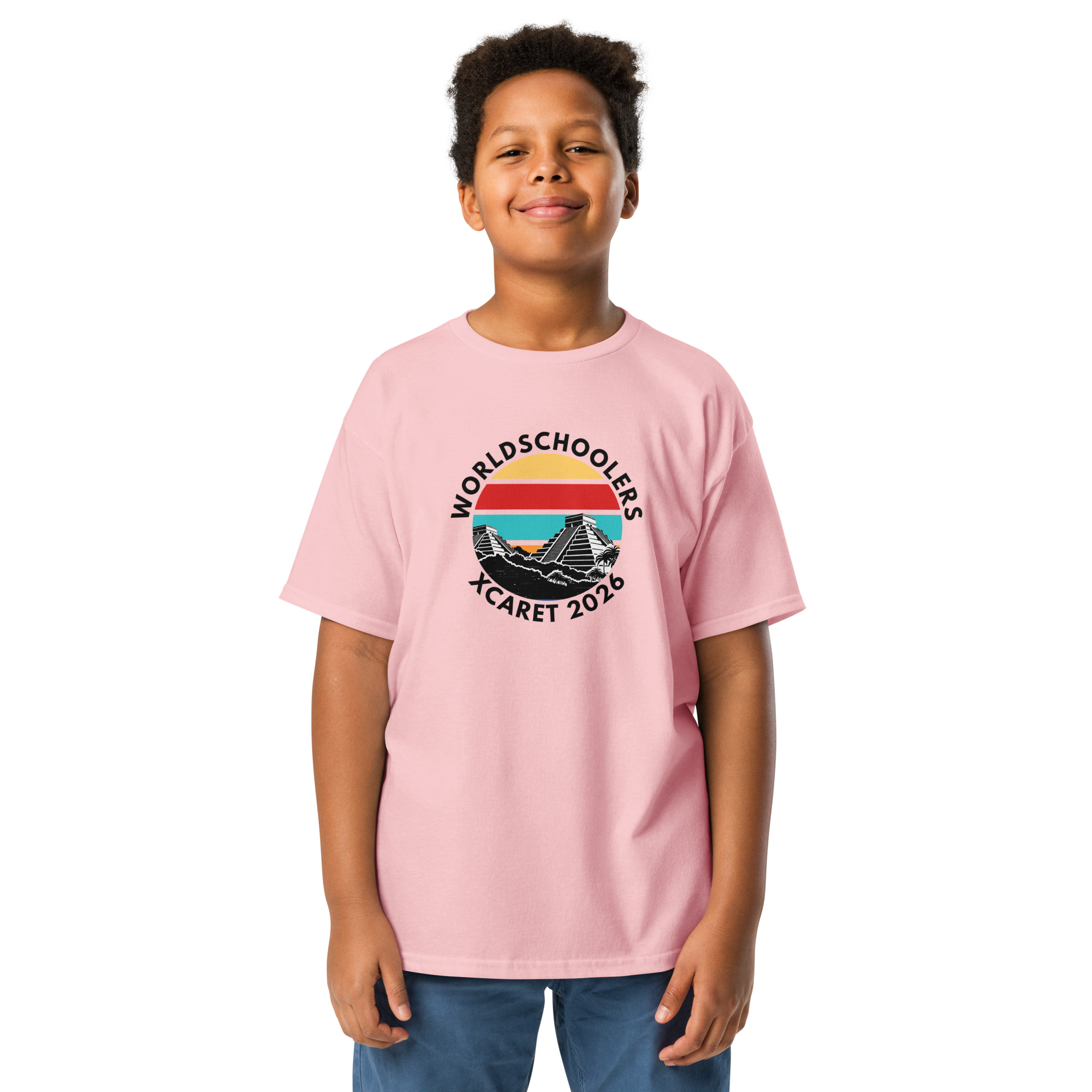 Young boy wearing a pink Xcaret 2026 Youth Classic T-shirt with a graphic design, promoting the Xcaret 2026 event. Perfect for kids' casual and event wear.