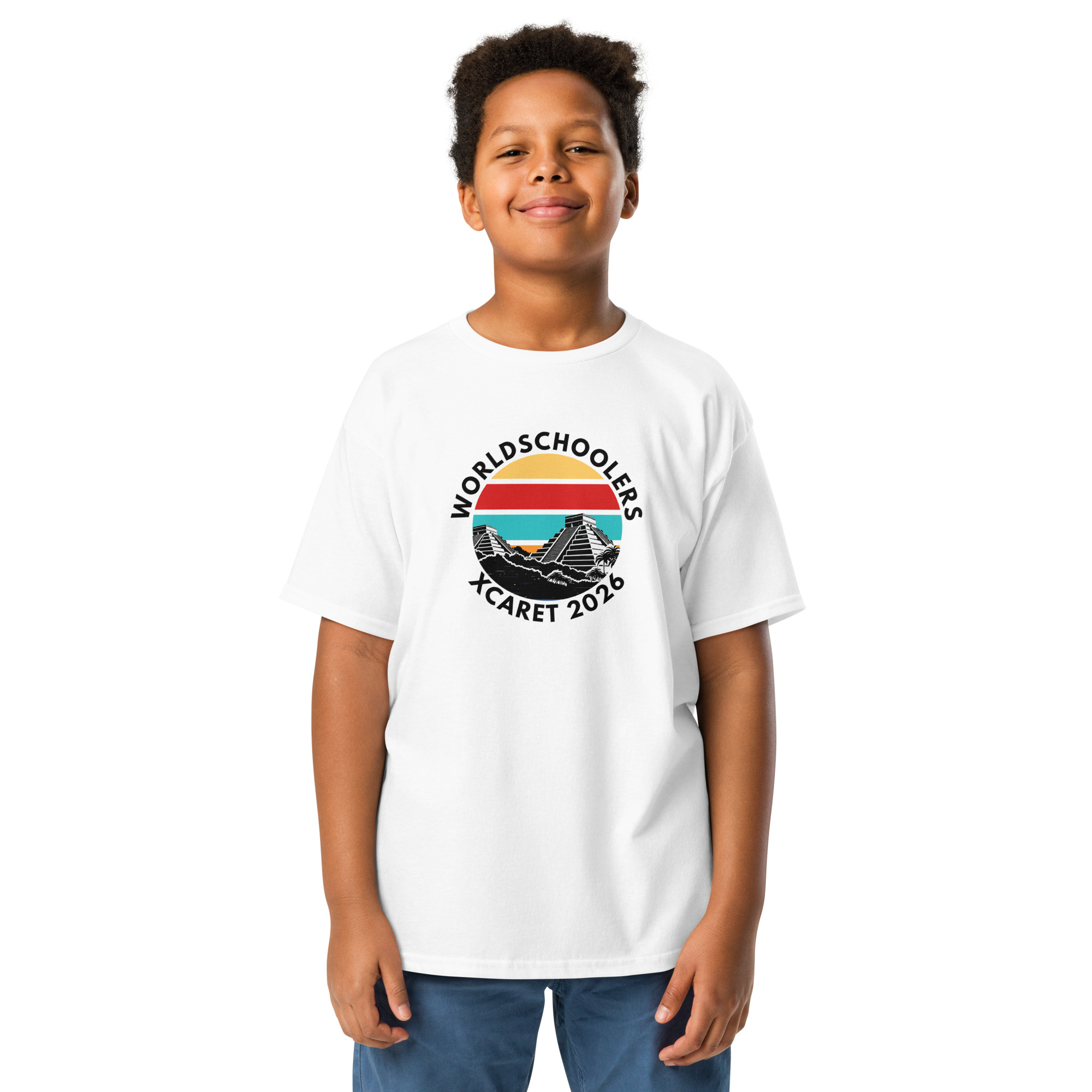 Child wearing a white Xcaret 2026 youth classic graphic tee with mountain and sunset design, promoting Xcaret 2026 event.