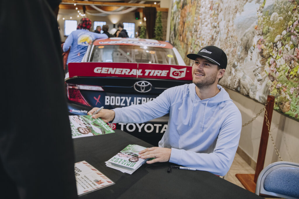 Todd Gilliland signing autographs at the Thanksgiving dinner hosted by Higgins United Methodist Church