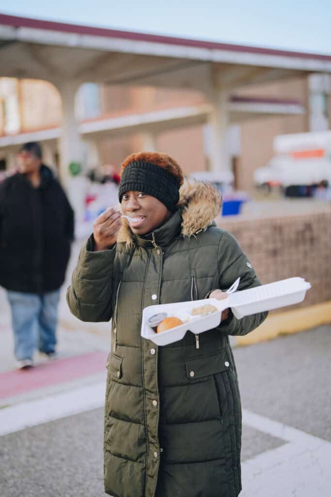 Attendees at the Community Christmas Giveaway in Norfolk, VA, receiving hot, chef-prepared meals served by Mercy Chefs.