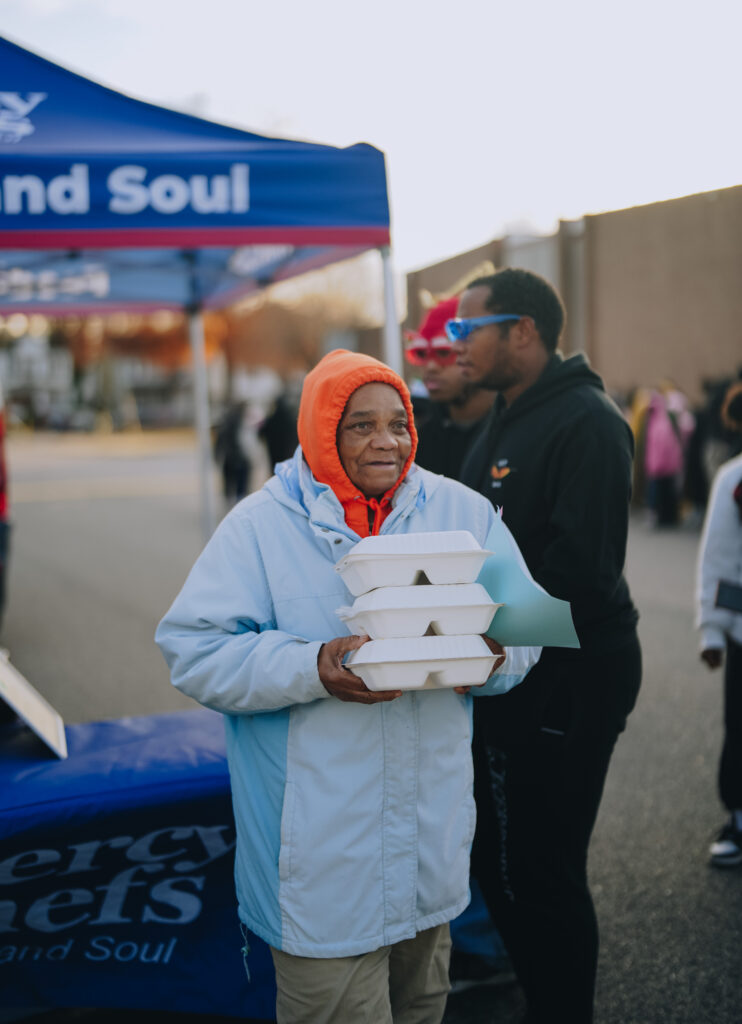 Attendees at the Community Christmas Giveaway in Norfolk, VA, receiving hot, chef-prepared meals served by Mercy Chefs.