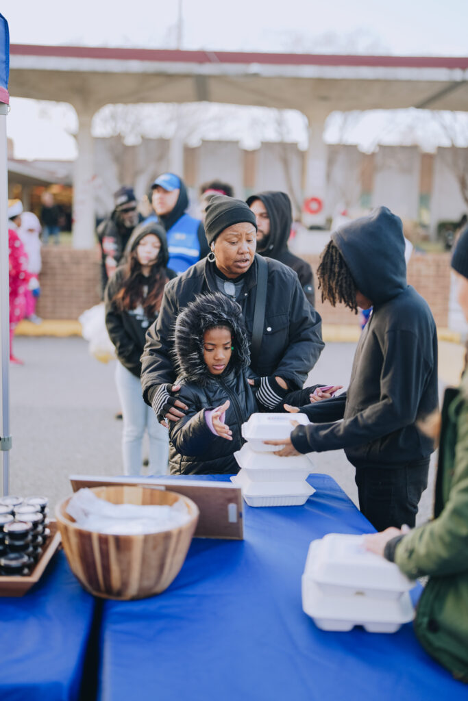 Attendees at the Community Christmas Giveaway in Norfolk, VA, receiving hot, chef-prepared meals served by Mercy Chefs.