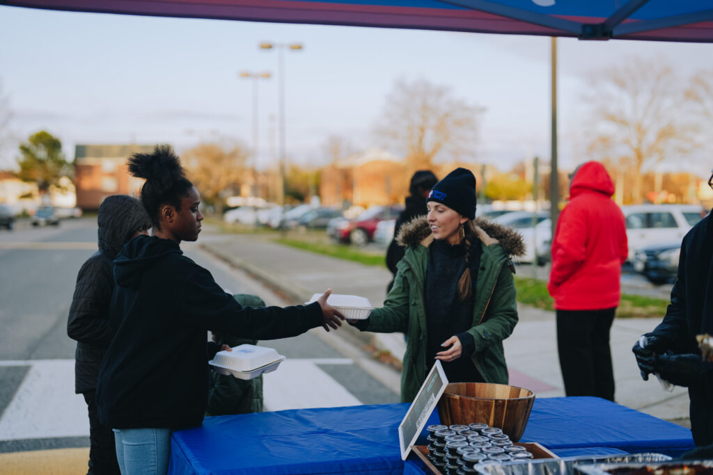 Attendees at the Community Christmas Giveaway in Norfolk, VA, receiving hot, chef-prepared meals served by Mercy Chefs.