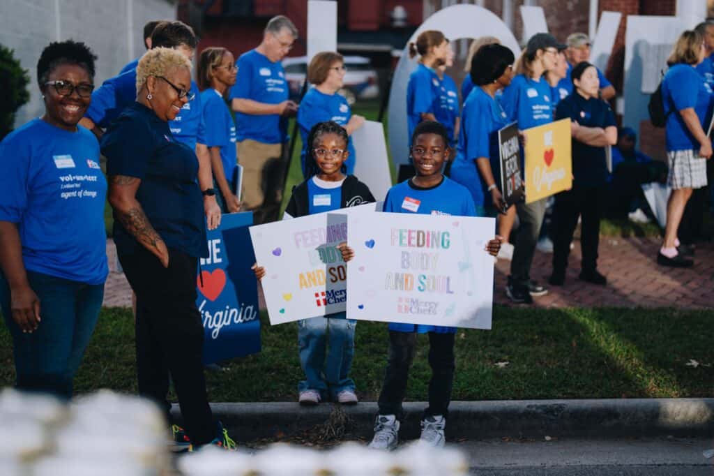 Children volunteers hold signs during a GMA live broadcast at Mercy Chefs' HQ