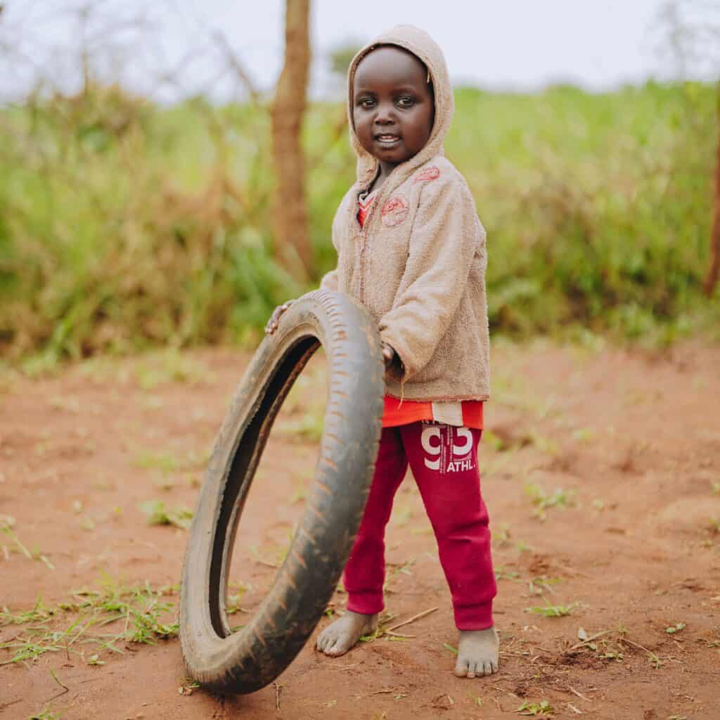 A Ugandan child holds a tire