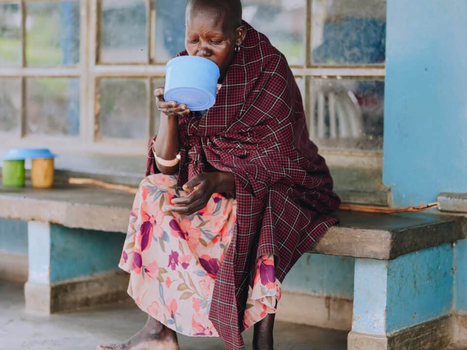 A woman drinks water in a Ugandan hospital