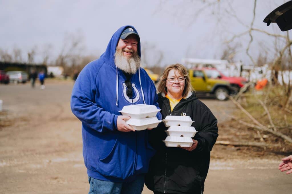A couple cleaning tornado debris in Illinois receives hot meals
