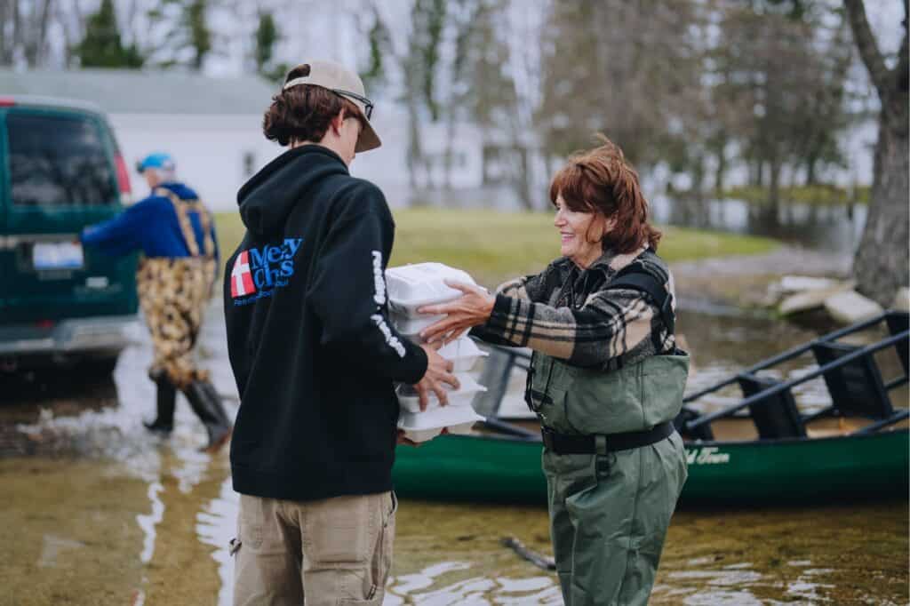 A Mercy Chefs staff member hands meals to a flood victim in Onaway, MI
