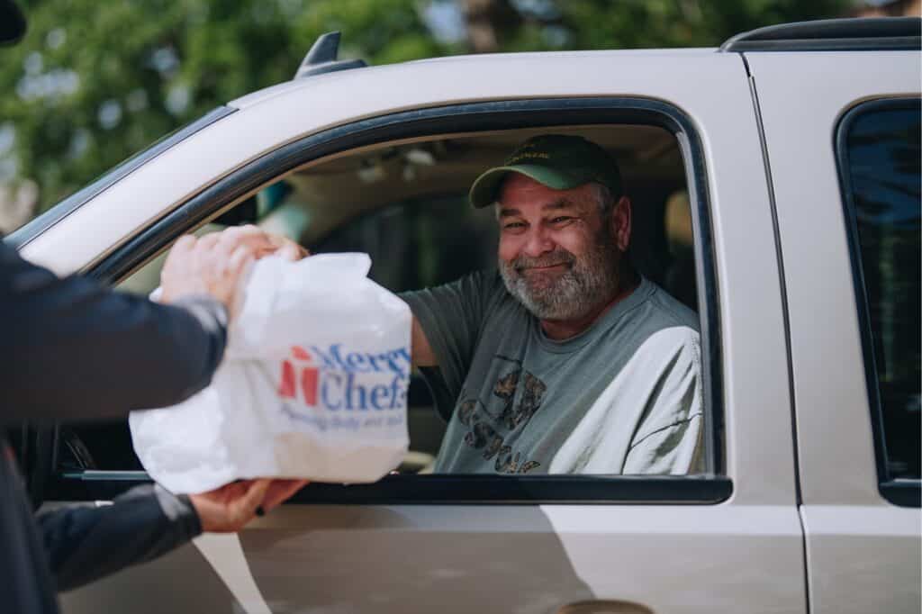 J.W. Michael smiles as he receives hot meals at a Mercy Chefs drive-thru in Texas