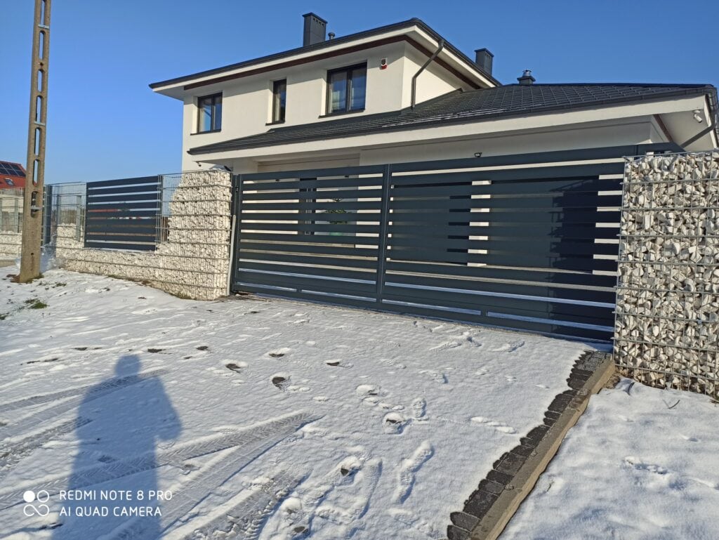 Przedstawia nowoczesną, solidną bramę przesuwaną wykonaną z metalu, idealną do ogrodzenia posesji. - ogrodzenie Metal-Serwis Obrzycko.
