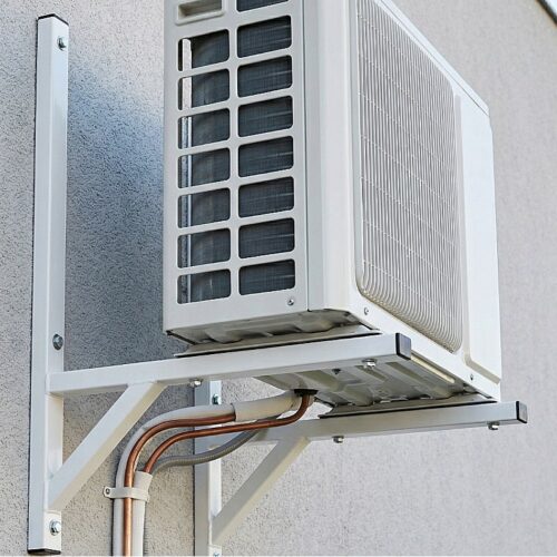 Klimatyzator ścienny z metalowym obudową, zamontowany na ścianie budynku - ogrodzenie Metal-Serwis Obrzycko.