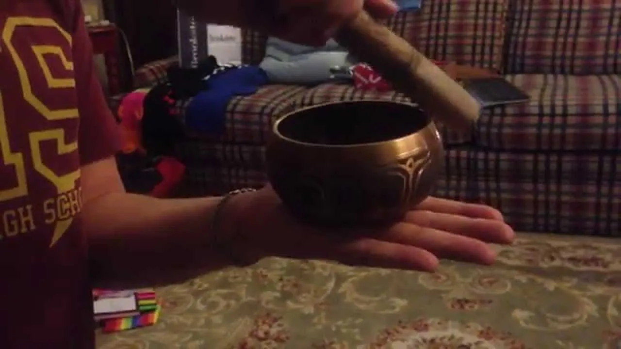 Person holding a traditional Buddhist singing bowl for meditation.