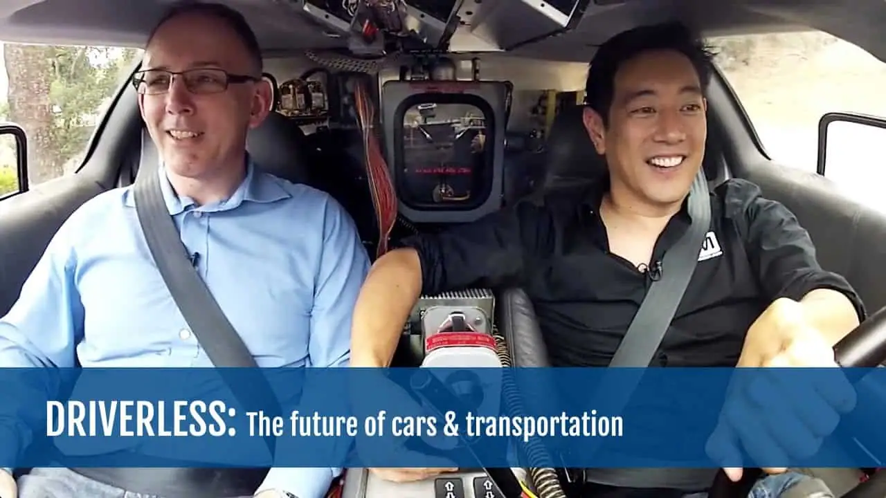 Two men in a driverless car, smiling and enjoying the ride.