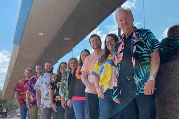 Team of diverse professionals standing outdoors in front of a modern building with glass windows.