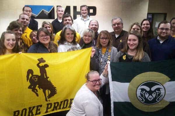 Group of diverse professionals holding Boke Pride flags outside MHP office.