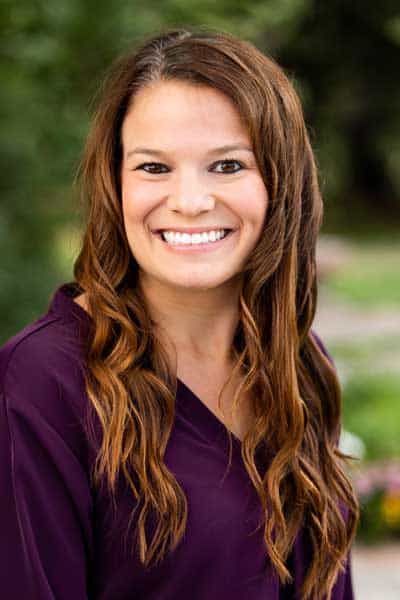 Healthy woman smiling outdoors in a park, representing wellness and health.