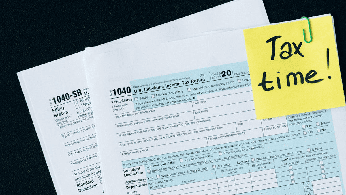 Tax documents and sticky note with "Tax time!" for MHP tax preparation services.