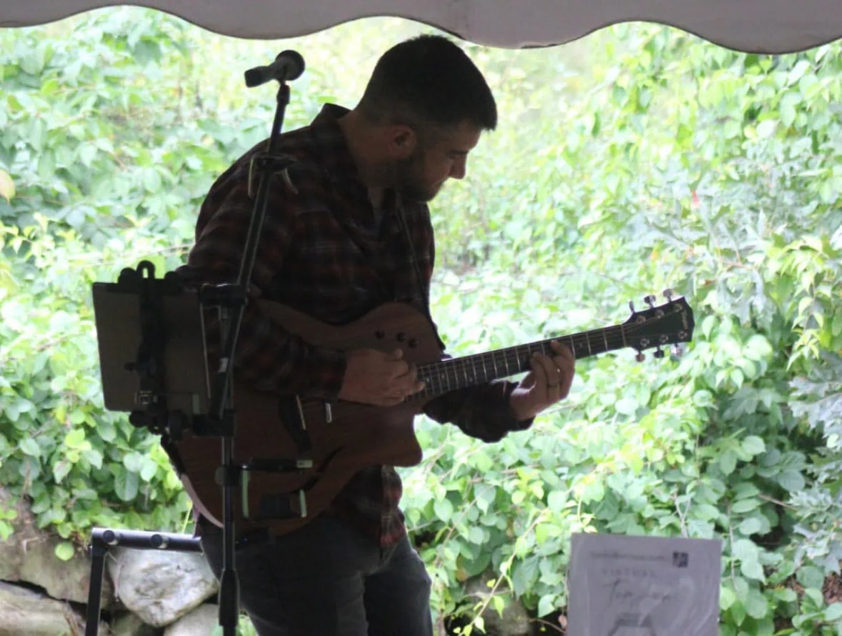 Musician playing guitar outdoors at Michael's Harborside event.