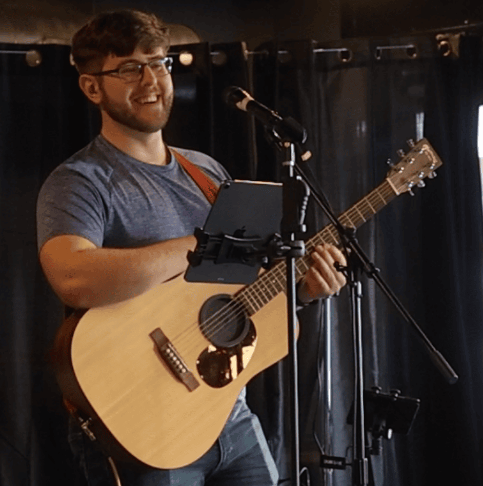 Man playing acoustic guitar and singing on stage at Michael's Harborside.
