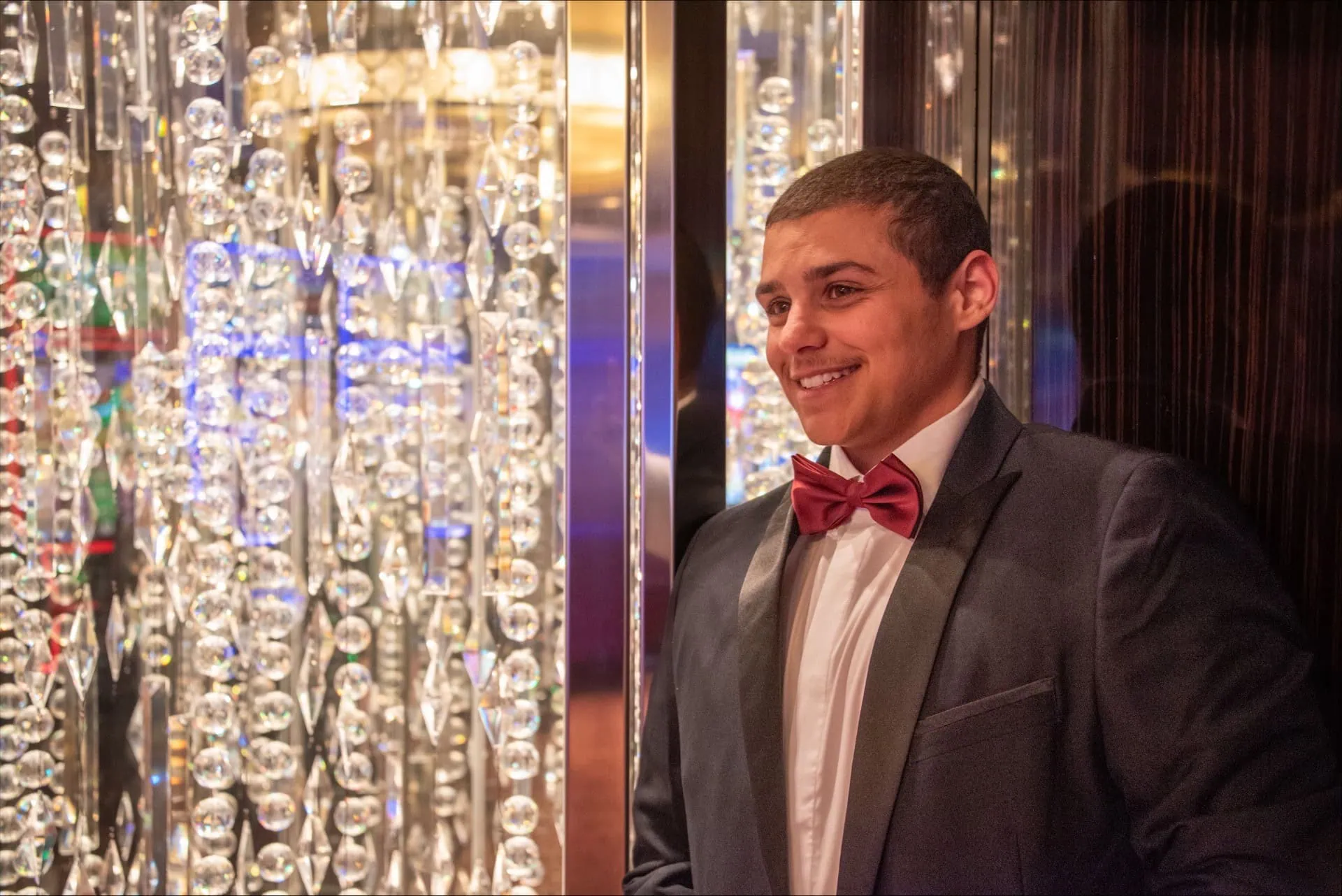 Young man in tuxedo with red bow tie smiling at Michael's Harborside event.
