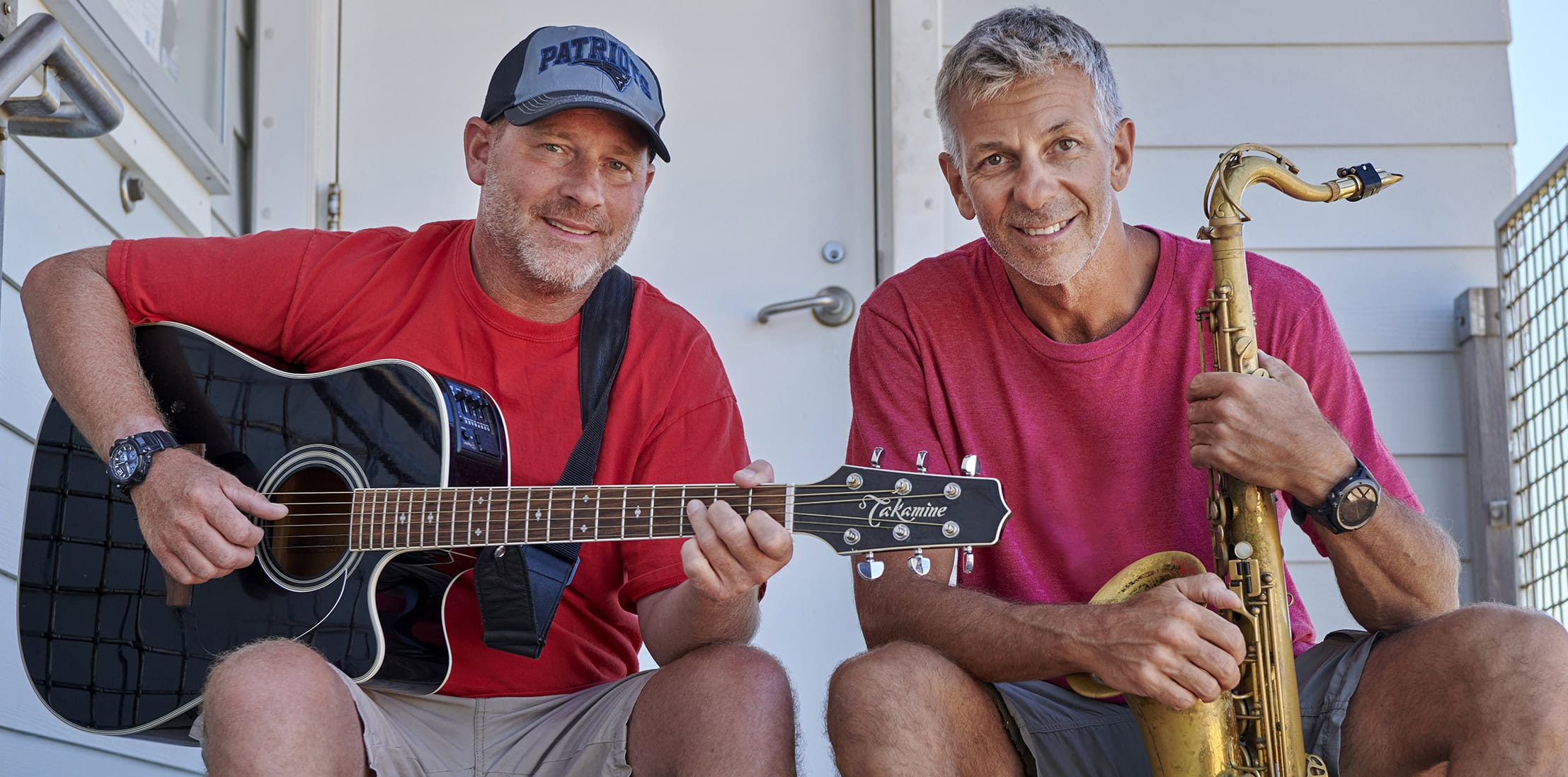 Two men playing guitar and saxophone on a porch at Michael's Harborside.