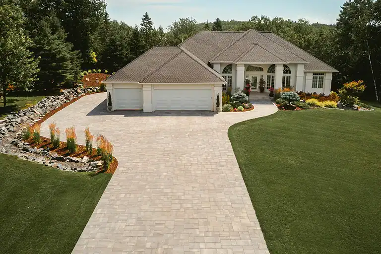 Beautiful landscaped lawn with a paved driveway leading to a modern home.