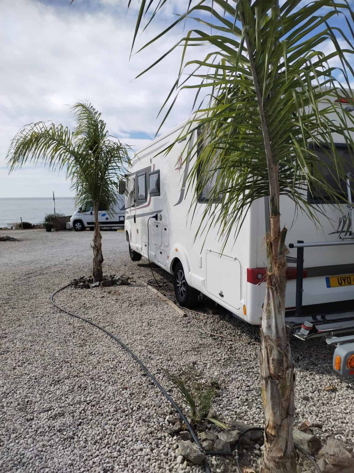 Camping car en área de MiluCar Torrox-Costa, con palmeras y vista al mar.