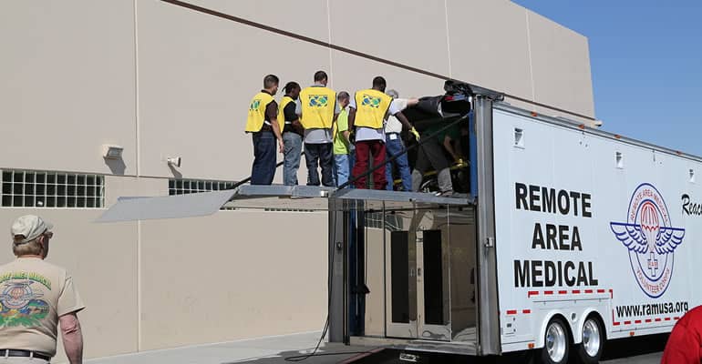 A group of people standing on the back of a truck.