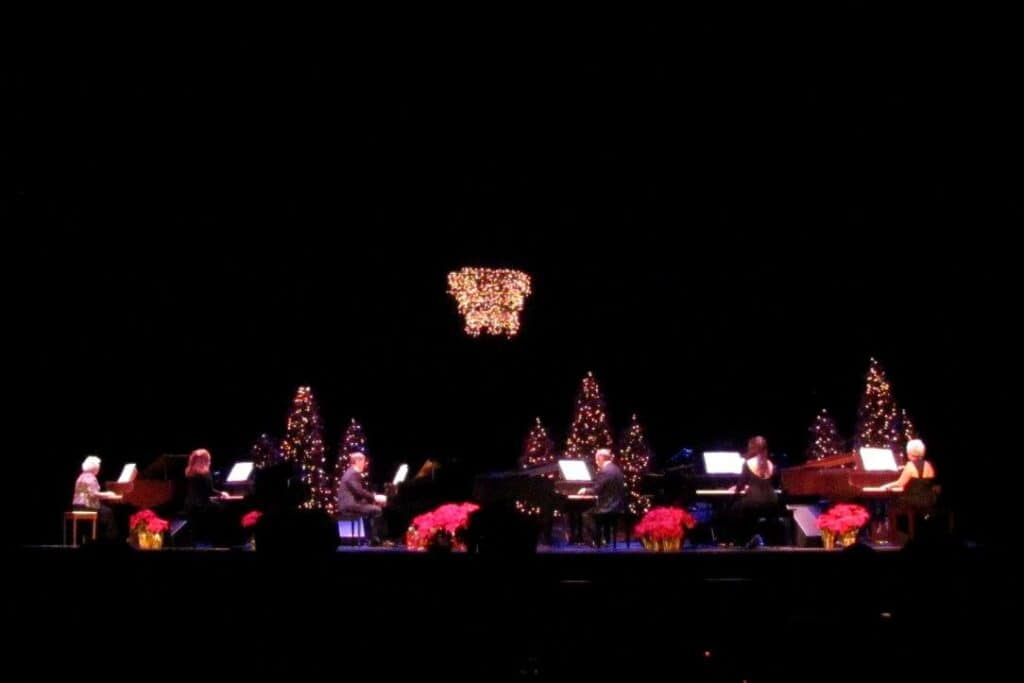 A group of people on stage in front of a christmas tree.