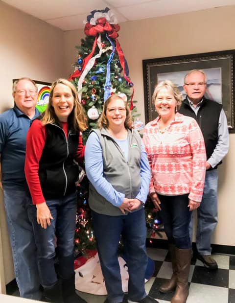 A group of people standing in front of a christmas tree.