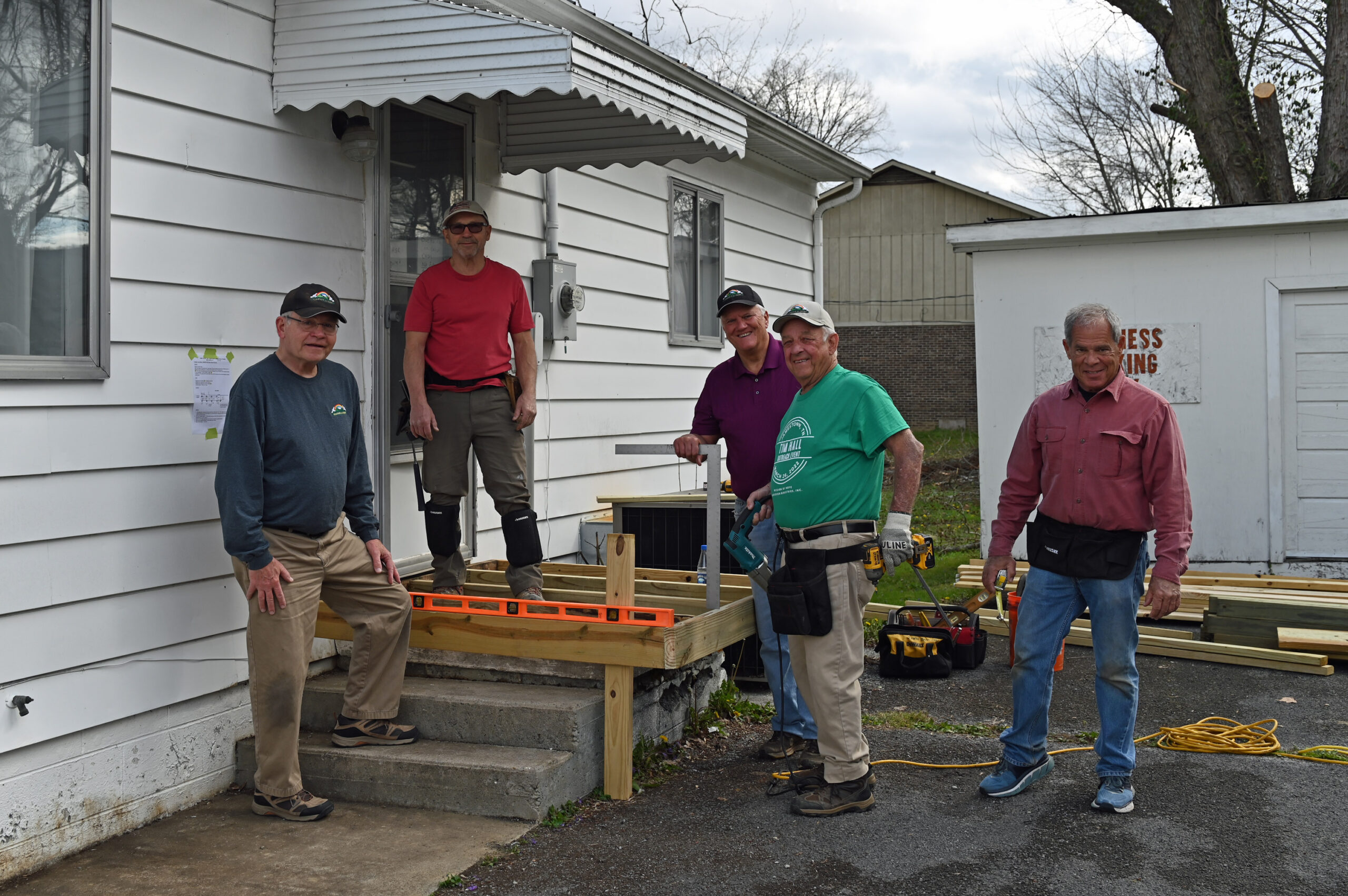DSC_4903.web50 A group of men standing on the steps of a house.