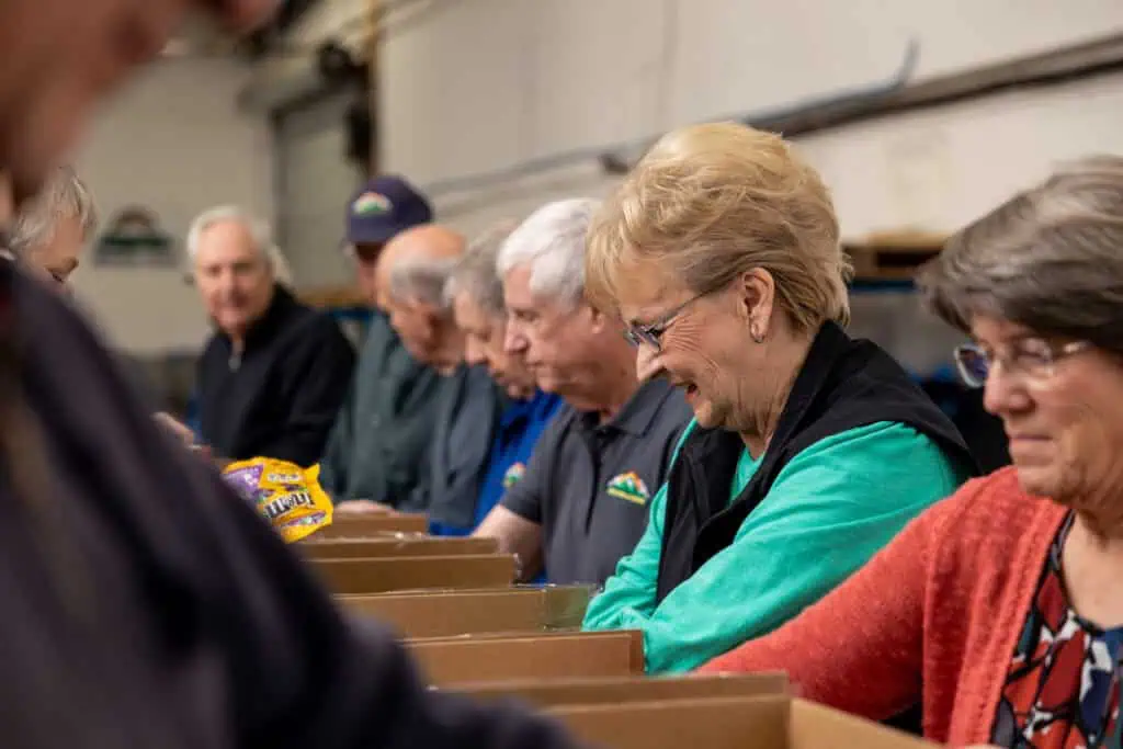 mission of hope 3.30.23-94 A group of older people standing in a warehouse.