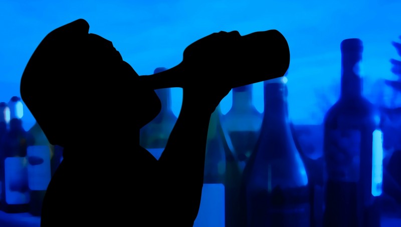 man drinking alcohol out of bottle