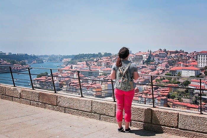 girl standing with back to camera looking out over city thinking about why to travel when you're young