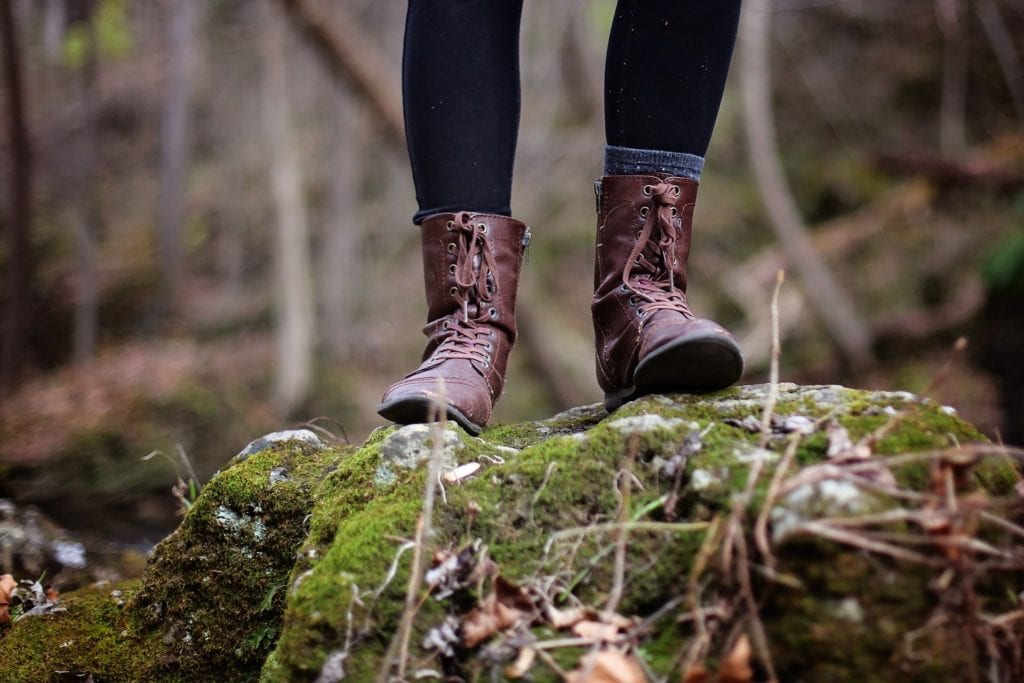 Girl's feet standing on mossy rock