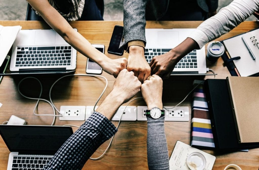 rawpixel via Pixabay group fist bump over table with laptops