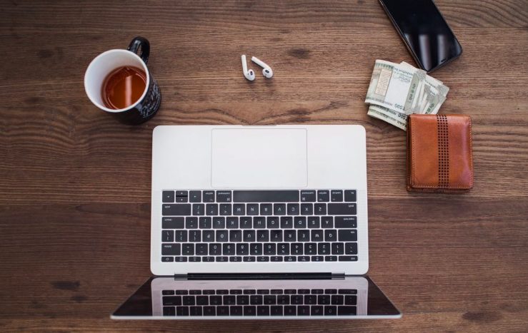 table with laptop phone headphones money