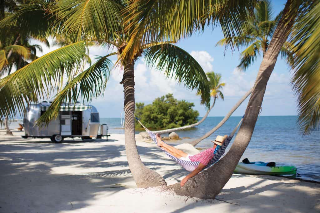 Man relaxing in a hammock with a vehicle in the background (RV)