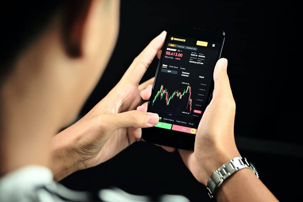 Man looking at cryptocurrency stocks on cell phone